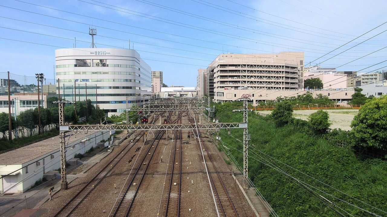線路の上の歩道橋から見た新百合ヶ丘駅の方向。線路の両側に大きな建物が並ぶ