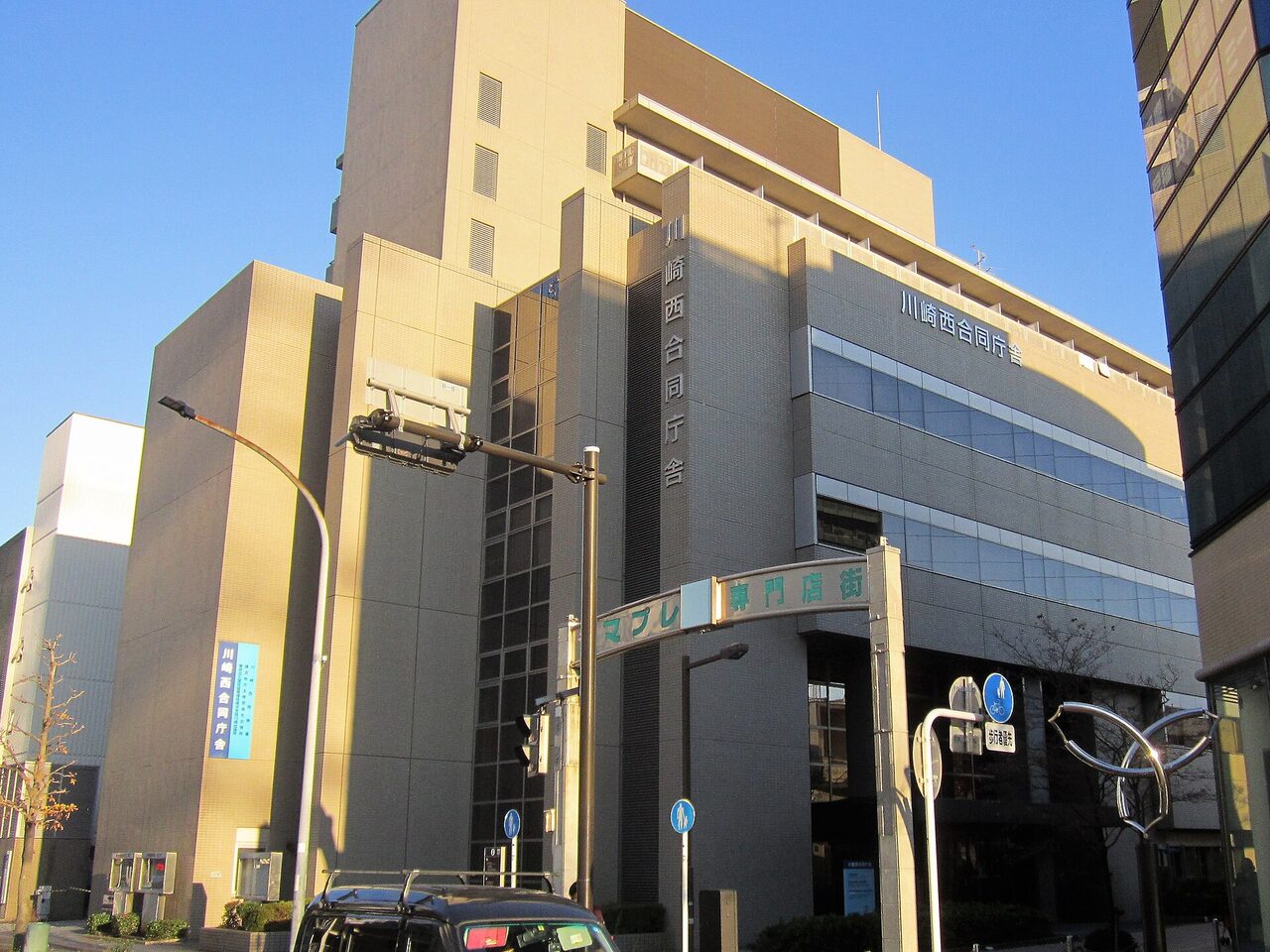 川崎西合同庁舎の外観。ベージュの壁の高い建物に「川崎西合同庁舎」の文字があり、手前に「マプレ専門店街」の看板が見える