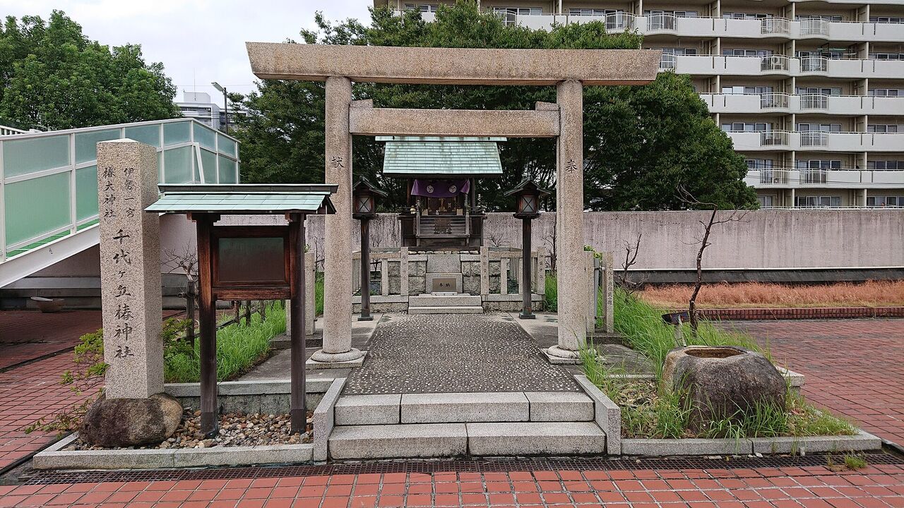 千代ヶ丘椿神社。石の鳥居の奥に小さな社があり、左に社名を刻んだ石柱、奥に集合住宅が見える