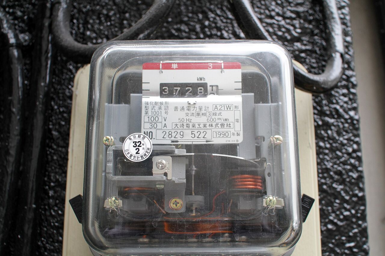 古い型の電力量計。透明なカバーの中に、数字の窓と回る円盤が見える