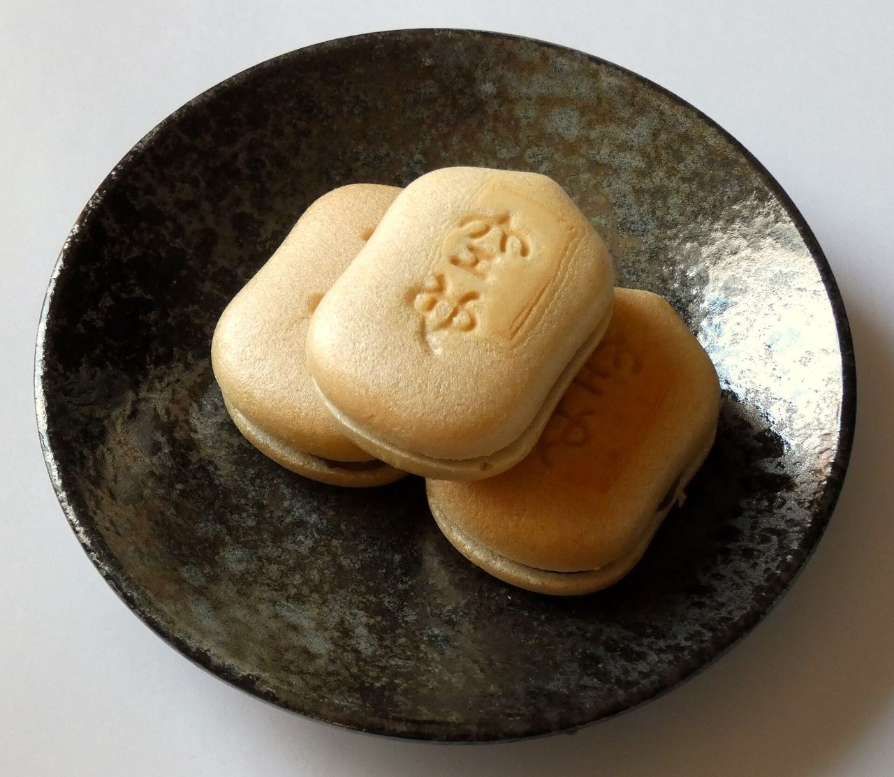 黒い皿に、ひょうたんのような形の最中が3つ。皮に文字の型押しがある
