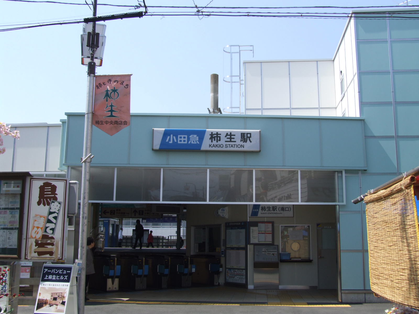 柿生駅の南口（2008年4月撮影）。駅名の看板の左に、「柿と寺のまち　柿生」と書かれた旗が下がっている