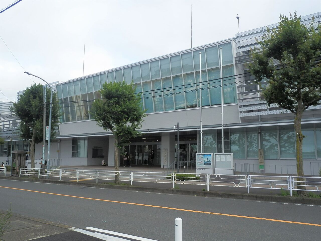 神奈川県警察運転免許センターの建物。ガラス張りの入口と、手前に街路樹がある