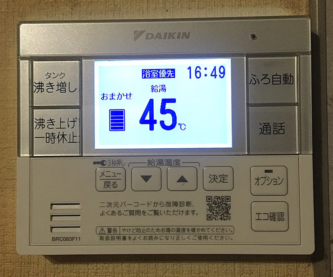 台所の壁にある、給湯の機械のリモコン。画面に「給湯 45℃」と時刻が表示され、まわりに温度を上げ下げするボタンが並ぶ