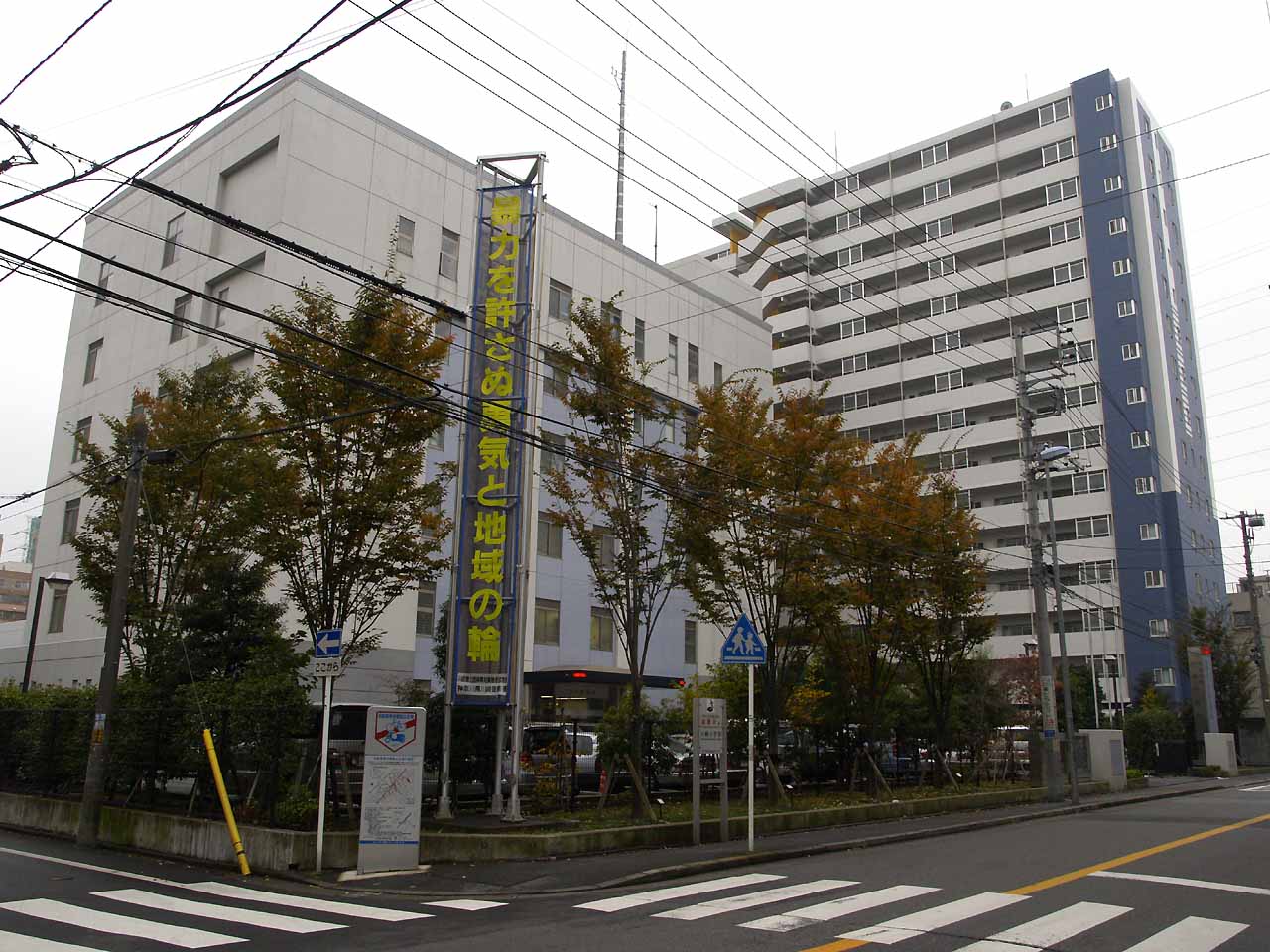 川崎警察署の建物。手前に横断歩道と、縦長の標語の看板がある