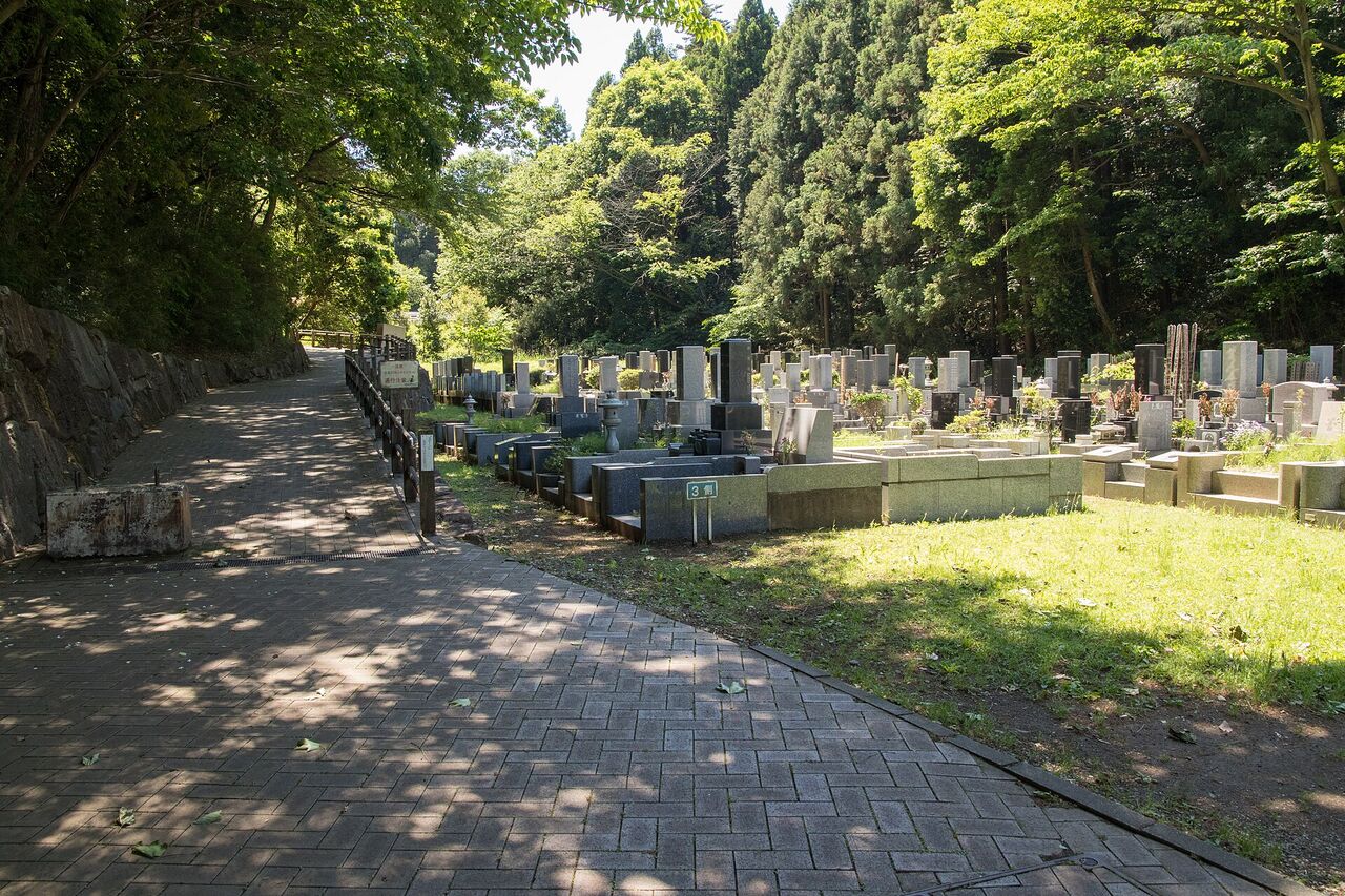 早野聖地公園の中の、木々に囲まれた石畳の道。右側に墓石が並んでいる