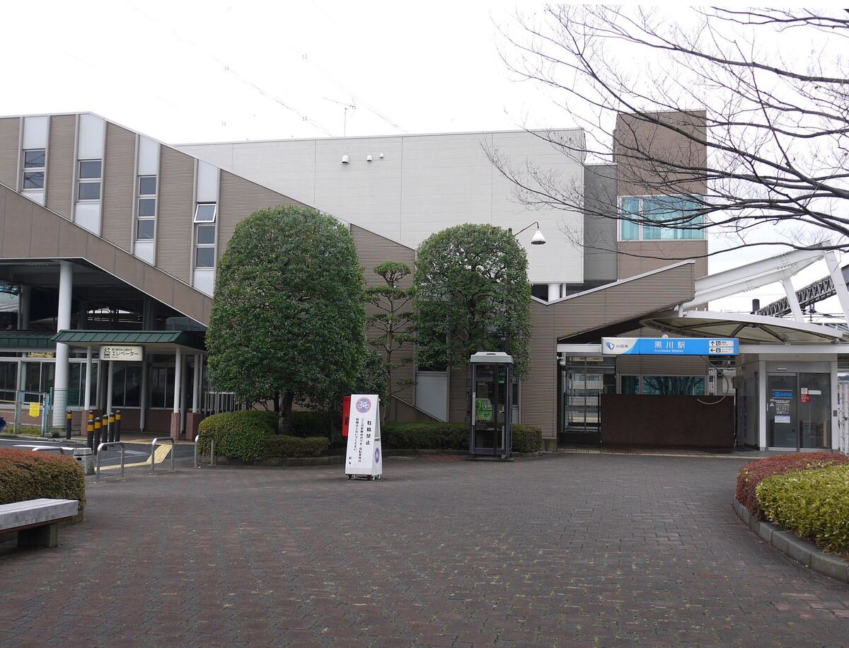 黒川駅の北口。階段とエレベーターの案内、駅名の看板、植え込みのある広場
