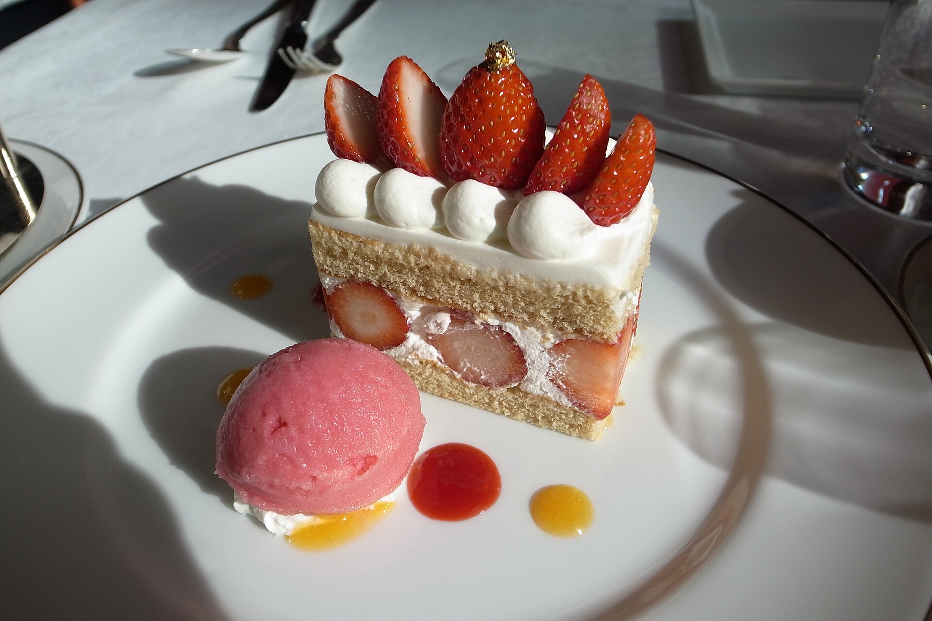 白い皿に、いちごをのせたショートケーキがひと切れと、ピンクのシャーベット