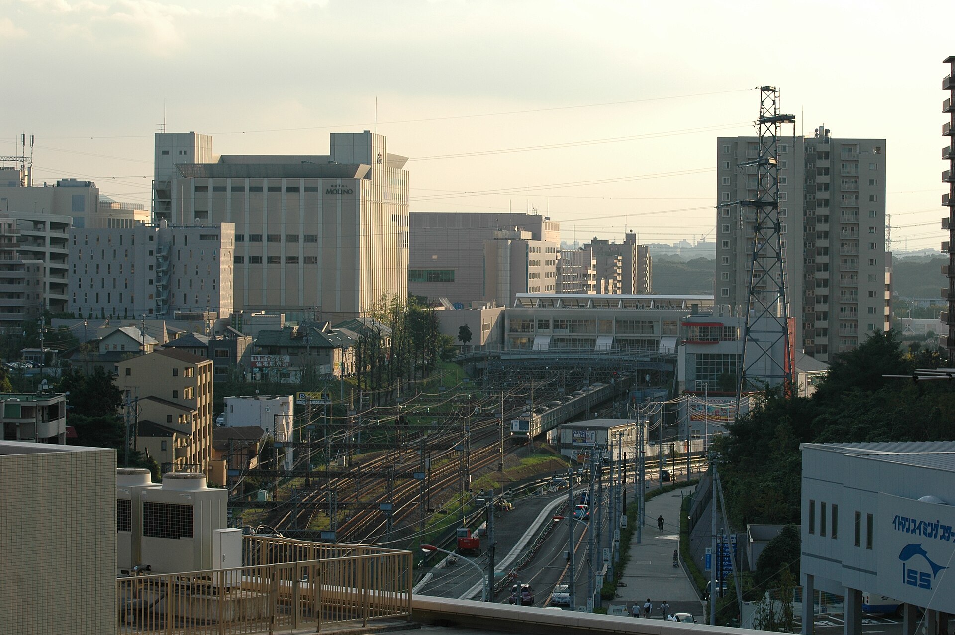 高い場所から見た新百合ヶ丘駅。線路の両側に大きな建物とマンションが並ぶ