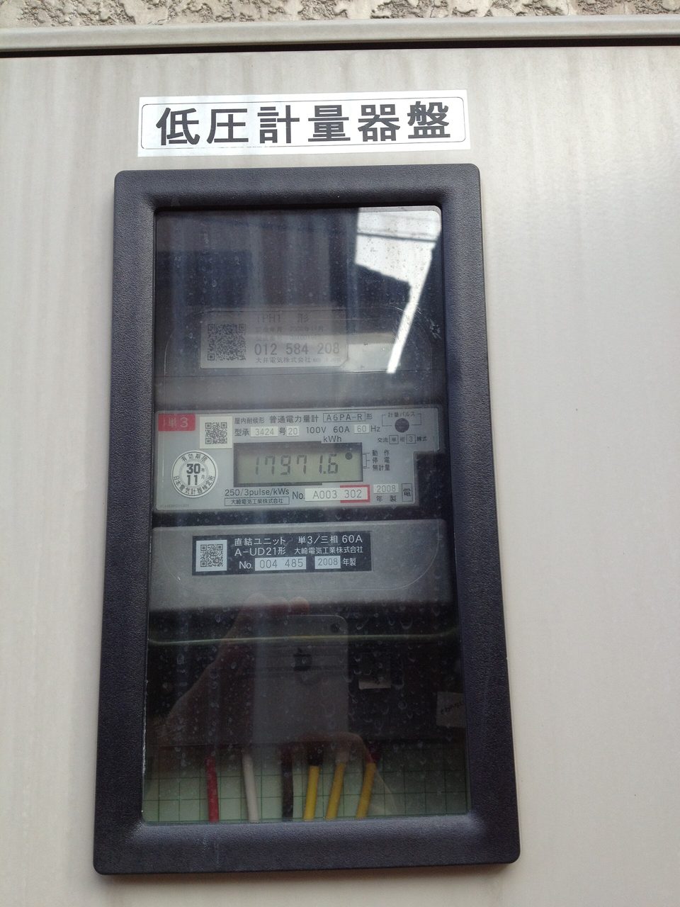 外壁の箱の中にある電気のメーター。上に「低圧計量器盤」と書いた札があり、ガラスの窓の中に数字の表示が見える