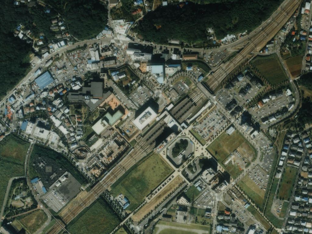 1989年の新百合ヶ丘駅の上空写真。駅前に大きな建物や駐車場、道路が整い、まわりに住宅が並んでいる